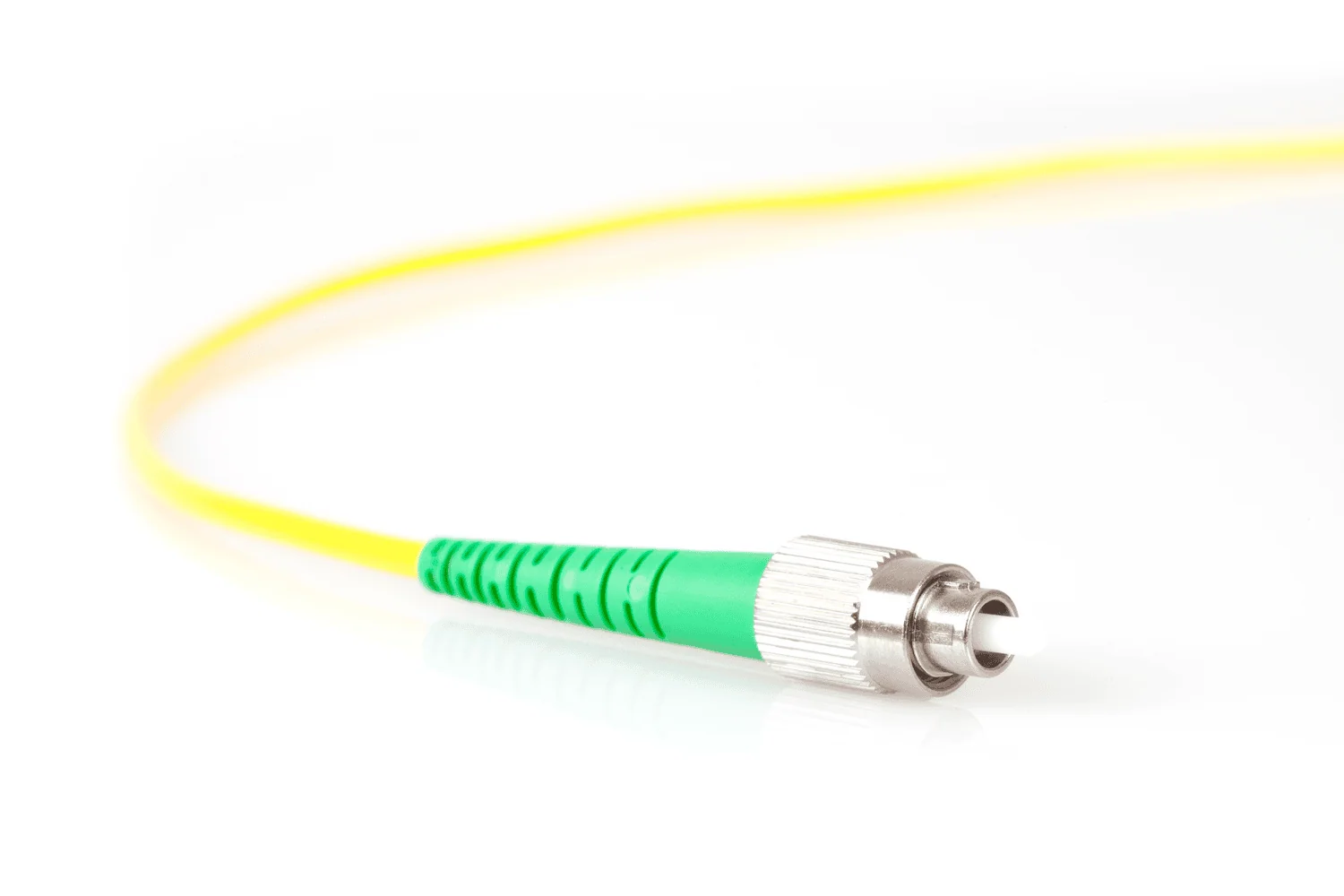 A close-up of a yellow fibre optic cable that terminates in a silver connector with a green, textured plastic housing, likely a single-mode SC/APC type.